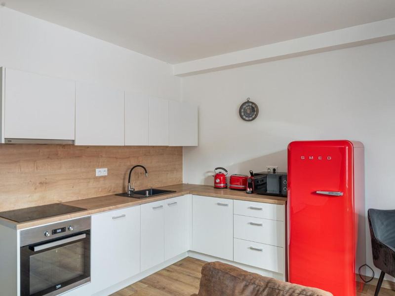 Modern kitchen with oven, hob and red fridge